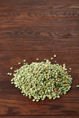 Pile of green peas on rustic wooden background, close-up, top view, selective focus.