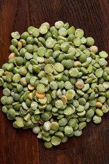 Pile of green peas on rustic wooden background, close-up, top view, selective focus.