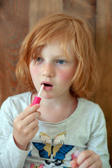 The girl paints lips with brilliance