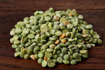 Pile of green peas on rustic wooden background, close-up, top view, selective focus.
