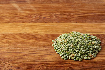 Pile of green peas on rustic wooden background, close-up, top view, selective focus.