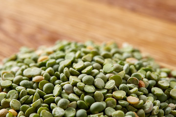Pile of green peas on rustic wooden background, close-up, top view, selective focus.