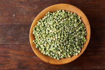 Nutritious green peas in a bowl and plate on rustic wooden background, close-up, top view, selective focus.
