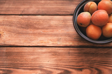 Bowl of raw apricots on a rustic wooden background  with a copy space for text