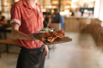 Waiter serving up a board of freshly baked nachos