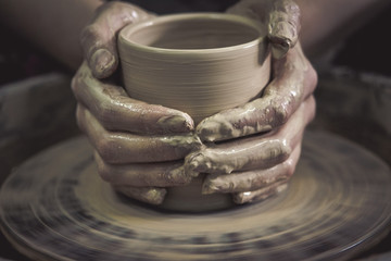Creating ceramic products of white clay close-up. The sculptor in workshop makes clay jug closeup. Master crock. Twisted potter's wheel. Art, creativity. Cultural traditions. Handmade. Craft.