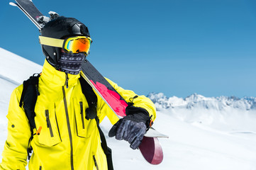 A portrait of a skier in a protective helmet and glasses is a mask and scarf with skis on his...