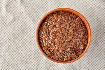 Close-up buckwheat in a round wooden plate over homespun tablecloth, top view, selective focus.