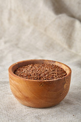 Close-up buckwheat in a round wooden plate over homespun tablecloth, top view, selective focus.