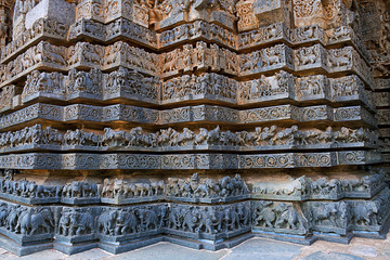 Friezes of animals, scenes from mythological episodes from Ramayana and Mahabharata, at the base of temple, Hoysaleshwara temple, Halebidu, Karnataka. View from West.
