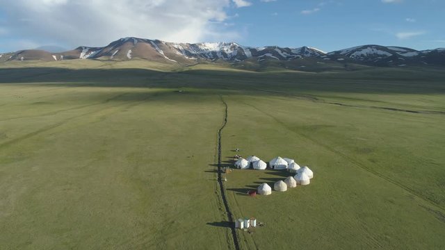 Yurts in Valley and Mountains on Background in Sunny Summer Day. Aerial View. Drone is Orbiting Around