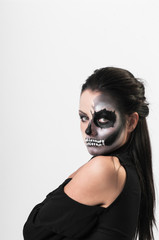 Studio portrait of beauty brunette woman wearing black clothes with scary greasepaint on face standing on white background