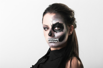 Studio portrait of beauty brunette woman wearing black clothes with scary greasepaint on face standing on white background