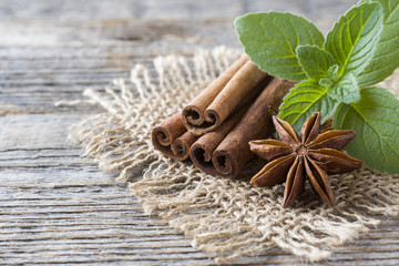 Cinnamon sticks and anise stars with mint on wooden background. Fragrant Oriental spice