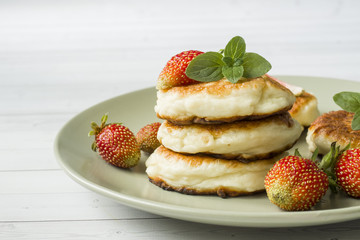 Curd pancakes with strawberries and mint on a plate