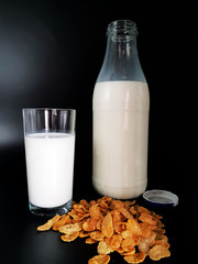 Milch im Glas mit Flasche auf schwarzem Hintergrund