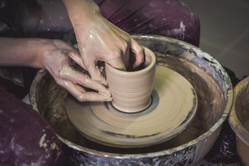 Creating ceramic products of white clay close-up. The sculptor in workshop makes clay jug closeup. Master crock. Twisted potter's wheel. Art creativity Cultural tradition Handmade Craft Master's Hands