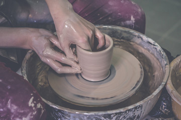 Creating ceramic products of white clay close-up. The sculptor in workshop makes clay jug closeup. Master crock. Twisted potter's wheel. Art creativity Cultural tradition Handmade Craft Master's Hands