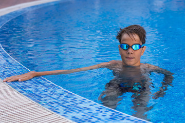 Portrait of a boy, athlete with swimming goggles in pool. Close up view.