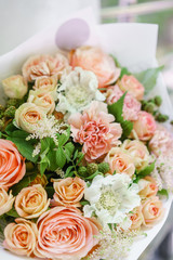 Work florist. Beautiful spring bouquet. Arrangement with mix flowers. The concept of a flower shop, a small family business. Color light peach and orange