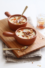 Baked Coconut Cream with Apricots and Crumble, in a little pot, on wooden board, on white background. 

