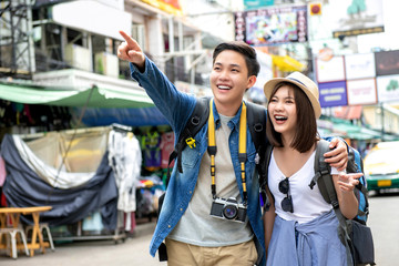 Young happy Asian couple tourist backpackers in Khao San road Bangkok Thailand - obrazy, fototapety, plakaty