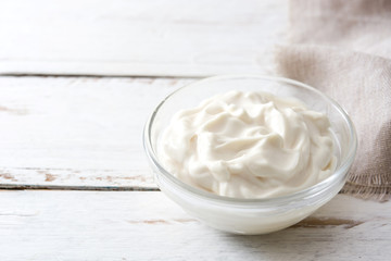 Sour cream in crystal bowl on white wood. Copyspace