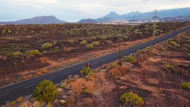 Aerial view of cyclist rider traveling up a desert road