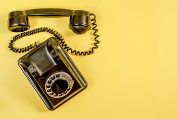 Vintage black telephone on yellow