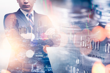 the double exposure image of businessman standing during sunrise overlay with cityscape and coin stack image. the concept of accounting, business, financial, economy and investment.
