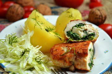 Stuffed chicken breast with spinach on a white plate with potatoes