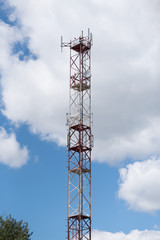 Technology on the top of the telecommunication GSM (4G) tower (antenna, transmitter), blue sky, white clouds.