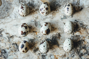 Quail eggs laid out in square on background of stone marble table