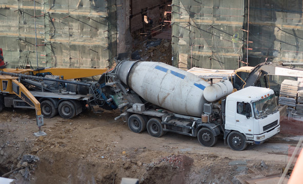 Workers at building site are pouring concrete in mold from mixer truck.
