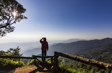 man standing on rock at sunset with mountains below