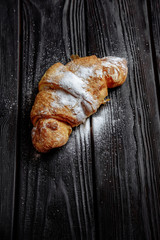 croissant on dark wooden background close-up top view