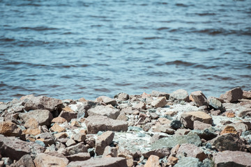 selective focus of rocky beach and wavy sea behind during daytime