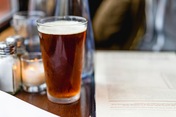 IPA beer next to a window at a rustic bar next to a menu
