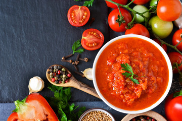 Tomato sauce with vegetables and spices on a black background. Sauce to pizza .Food background.