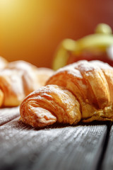croissants with tea on dark wooden background close-up sunlight