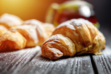 croissants with tea on dark wooden background close-up sunlight