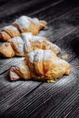 three croissants on dark wooden background close-up top view