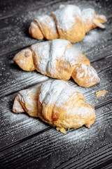 three croissants on dark wooden background close-up top view