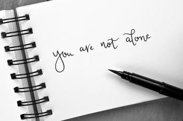 YOU ARE NOT ALONE hand-lettered in notepad