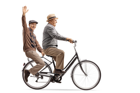 Seniors riding on a bicycle with one of them waving at the camera