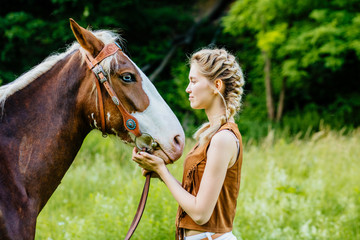 Obraz premium Beautiful blond two braids young woman with a horse face to face outdoor, side view, green background.