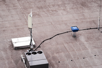 Roof of a commercial building with a external units of the commercial air conditioning and ventilation systems, cellular antenna and lightning rod. - obrazy, fototapety, plakaty
