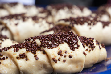 Fresh croissants decorated with chocolate chips are prepared for baking in the oven. Close-up