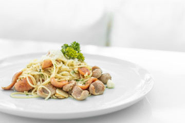 Closeup of Spaghetti and Sausage with stir fried chillies on white dish and with background. Italian style pasta dinner concept. Copy space