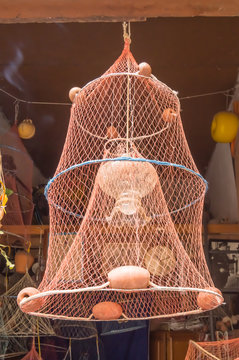 Crab fishing net turn into lamp hanging on the port of Cefalu